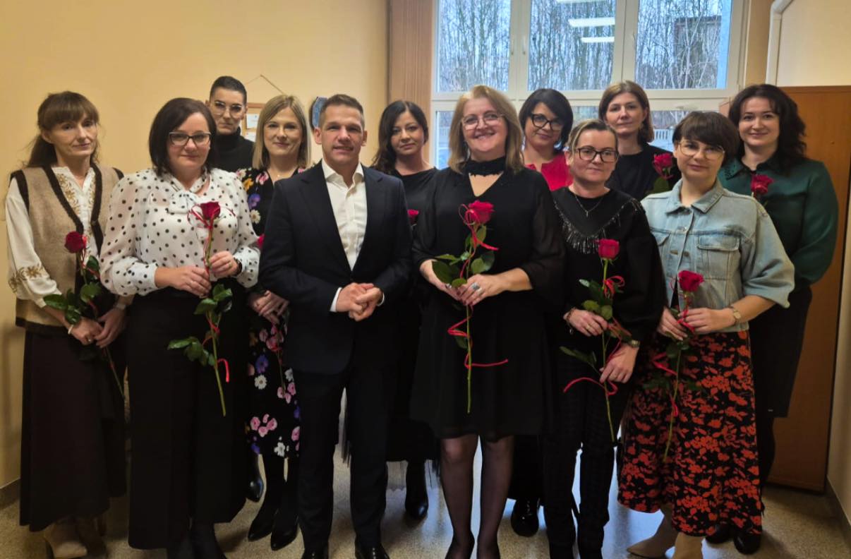 Mężczyzna z kobietami pozujący do zdjęcia. Kobiety w rękach trzymją kwiaty
